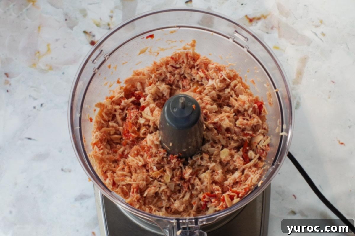 Zesty Mediterranean Chicken Rice Cups 6 Finely chopped chicken, garlic, and sun-dried tomatoes being processed in a food processor