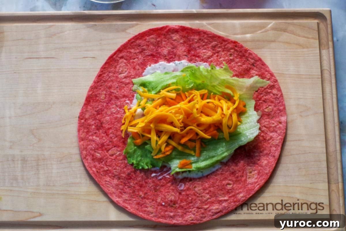 Ultimate Turkey Bacon Ranch Wrap 5 Tomato wrap with a colorful layer of ranch dressing, lettuce, shredded carrots, and cheddar cheese.