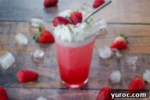 Strawberry Italian Soda in a glass with strawberries, sprinkles and ice surrounding it