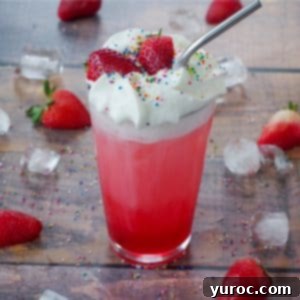 Strawberry Italian Bliss 7 Strawberry Italian Soda in a glass with strawberries, sprinkles and ice surrounding it