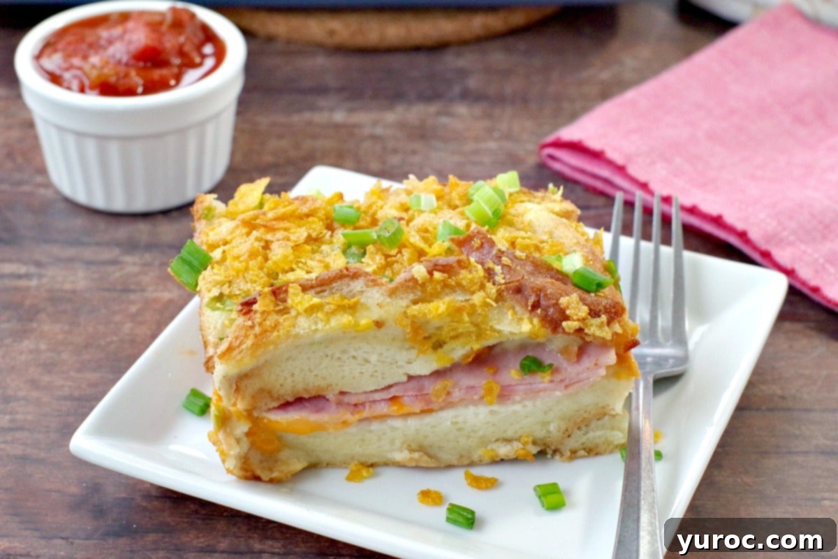 Stress-Free Christmas Breakfast Bake 4 A slice of Christmas morning casserole on a white plate, on brown wooden surface, with fork on red napkin beside it, salsa in a white dish behind