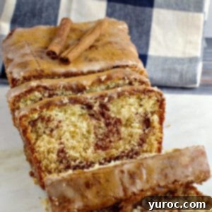 cinnamon loaf on marble cutting board with blue and white checkered tea towel in background