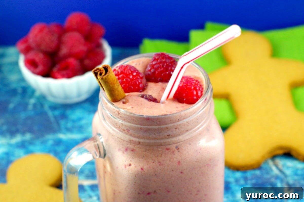 raspberry gingerbread smoothie with a bowl of raspberries and a gingerbread man in the background
