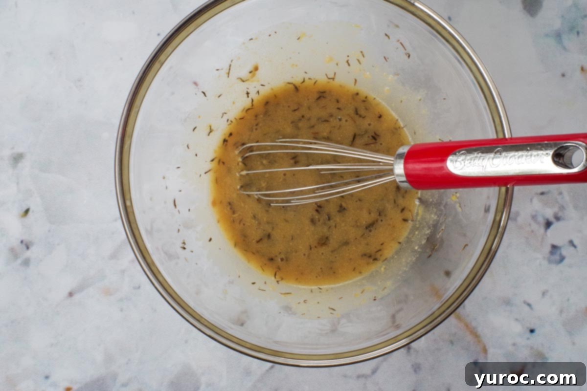 Marinade ingredients whisked together with a whisk in a glass bowl.