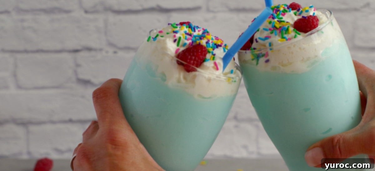 Two vibrant blue raspberry non-alcoholic drinks clinking together, symbolizing celebration and refreshment.