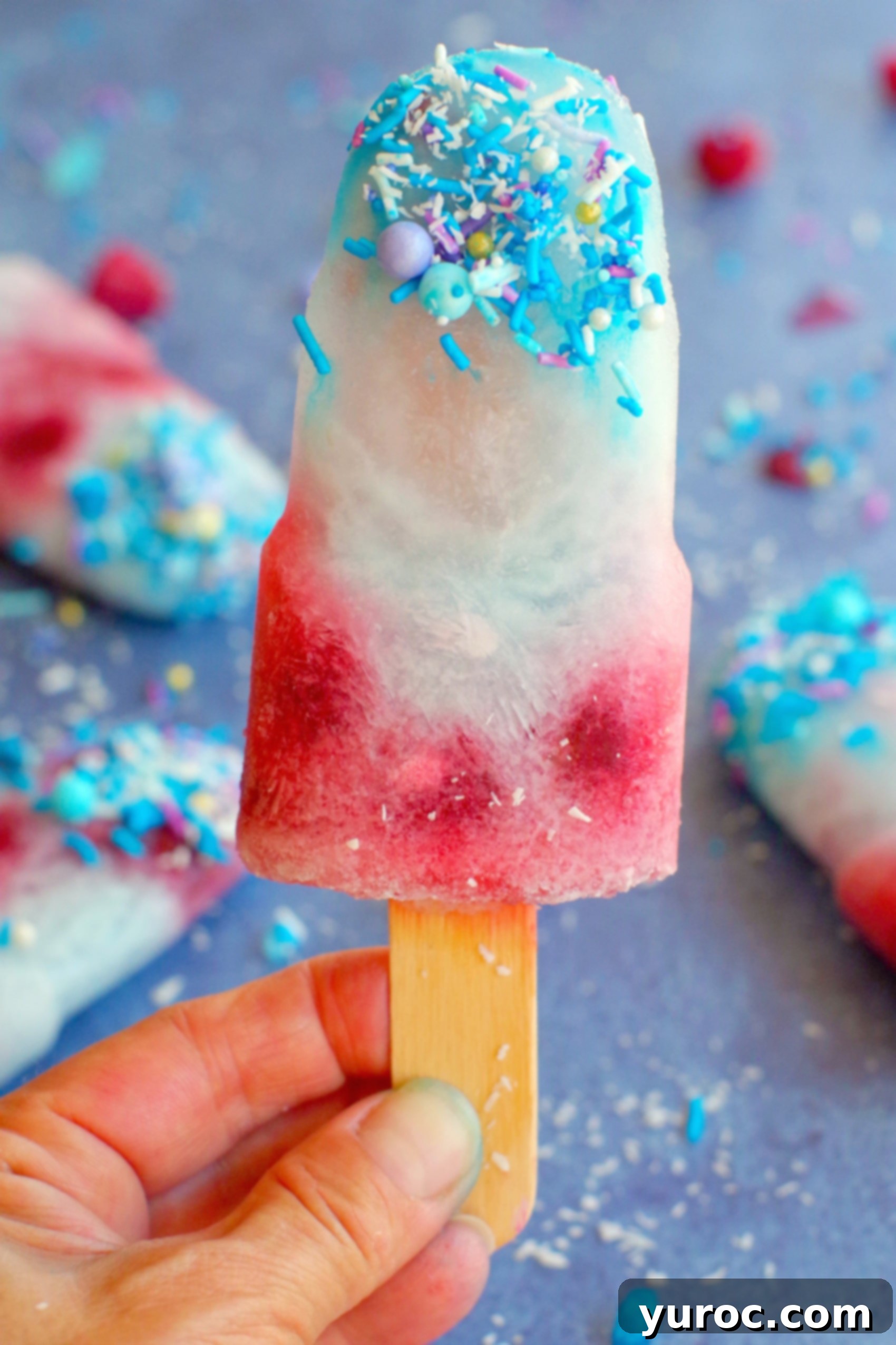 A single vibrant blue raspberry popsicle held aloft, showcasing its enticing color and refreshing appeal.
