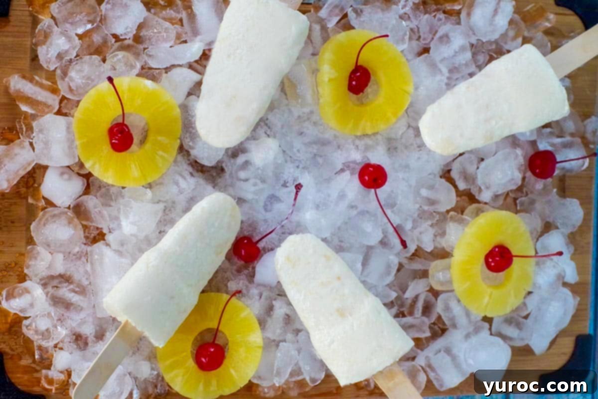 Tropical Pina Colada Popsicles served on a bed of ice, garnished with fresh pineapple wedges and maraschino cherries.