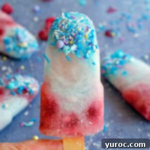 A close-up of a blue raspberry popsicle being held, with more popsicles visible in the background.