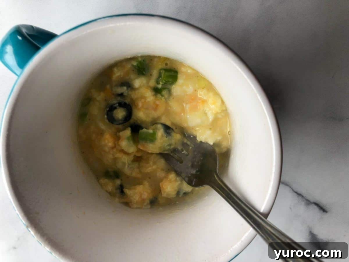 Partially cooked omelette being whisked again with a fork after a short microwave interval.