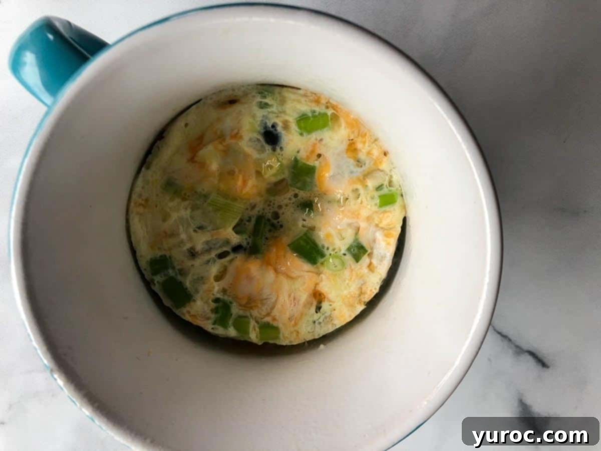 A fully cooked Microwave Omelette in a Mug, ready to be removed and garnished.