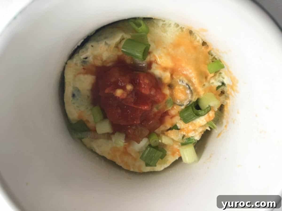 Microwave Omelette in a Mug generously garnished with vibrant fresh salsa, ready to be eaten.