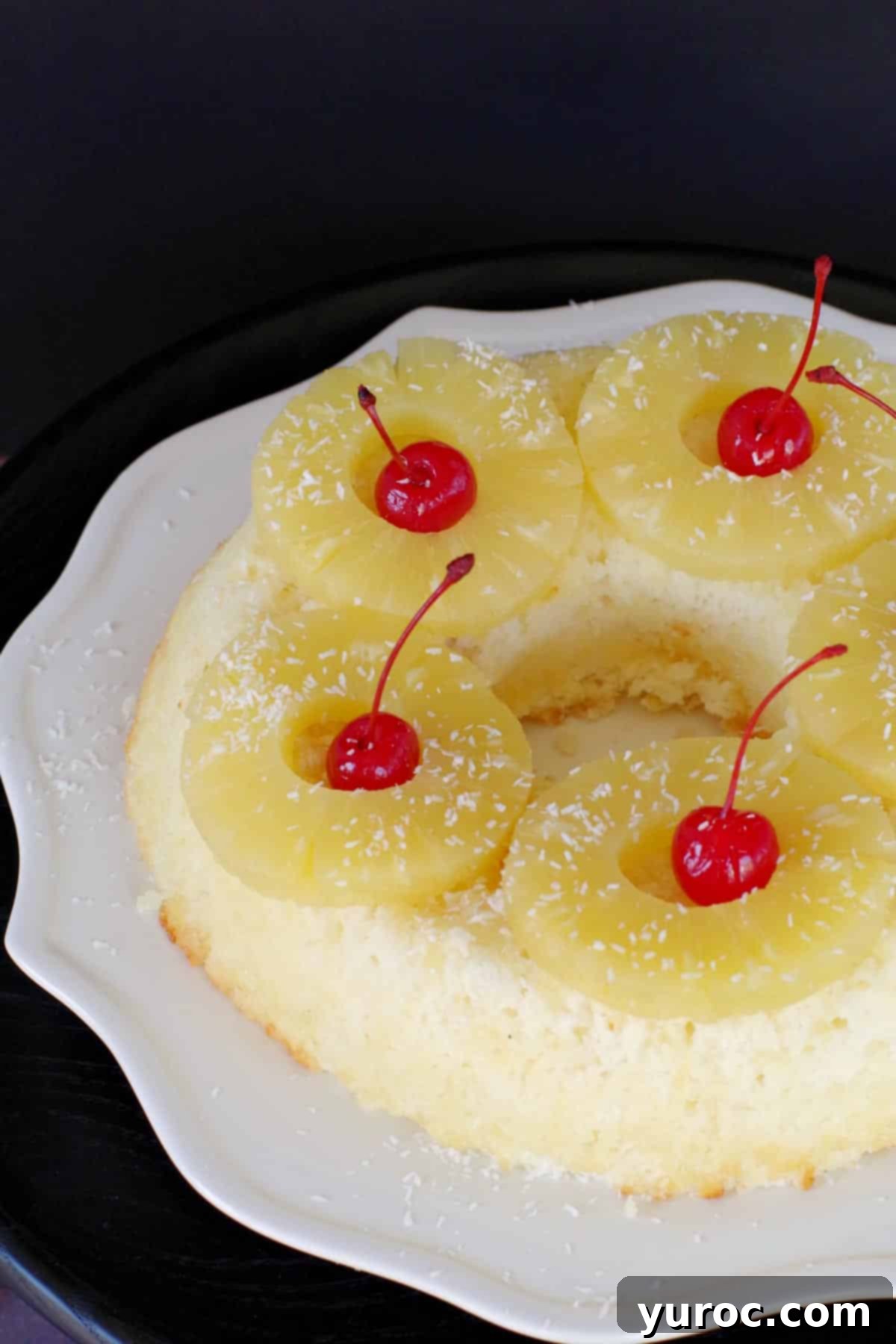 Weight Watchers Pina Colada Angel Food Cake, beautifully garnished with pineapple and cherries, on a white serving plate