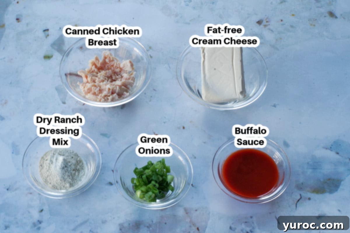 A collection of ingredients for Weight Watchers Buffalo Chicken Dip laid out in glass bowls, clearly labeled.