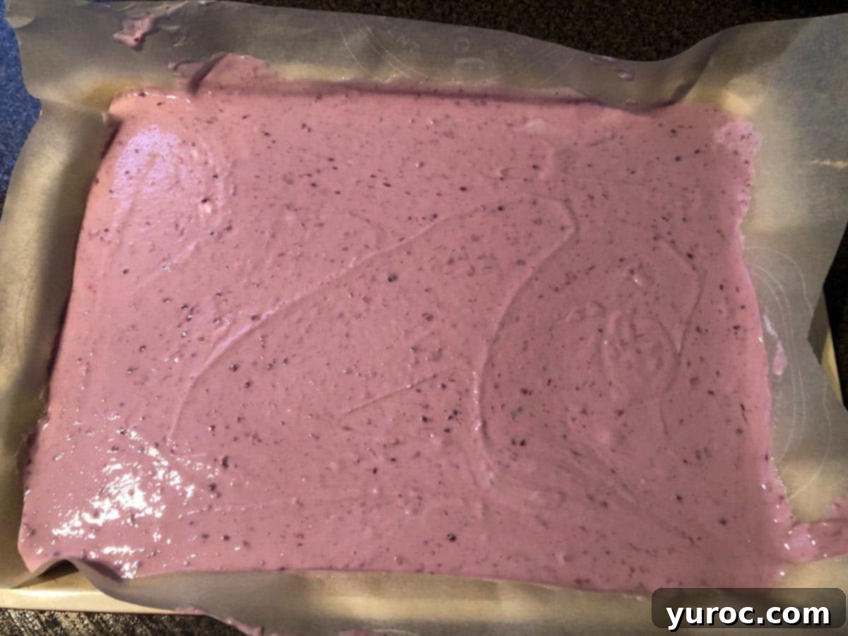 Raspberry yogurt mixture spread thinly on a parchment-covered baking sheet