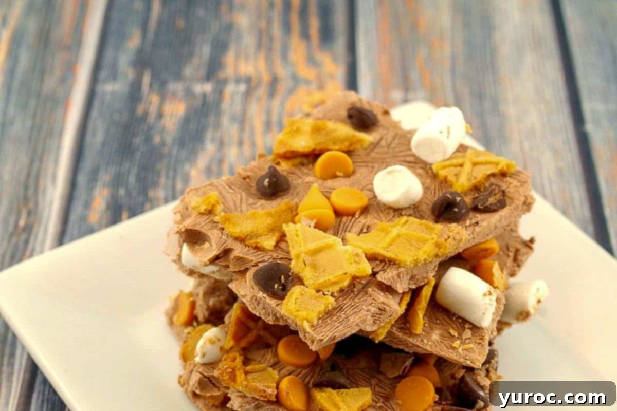 Several pieces of homemade Rocky Road frozen yogurt bark, layered with marshmallows and nuts, elegantly stacked on a white plate.