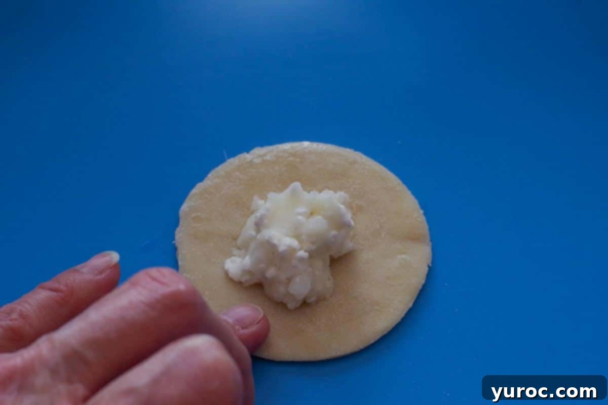 filling added to dough circle and finger rubbing water around the rim