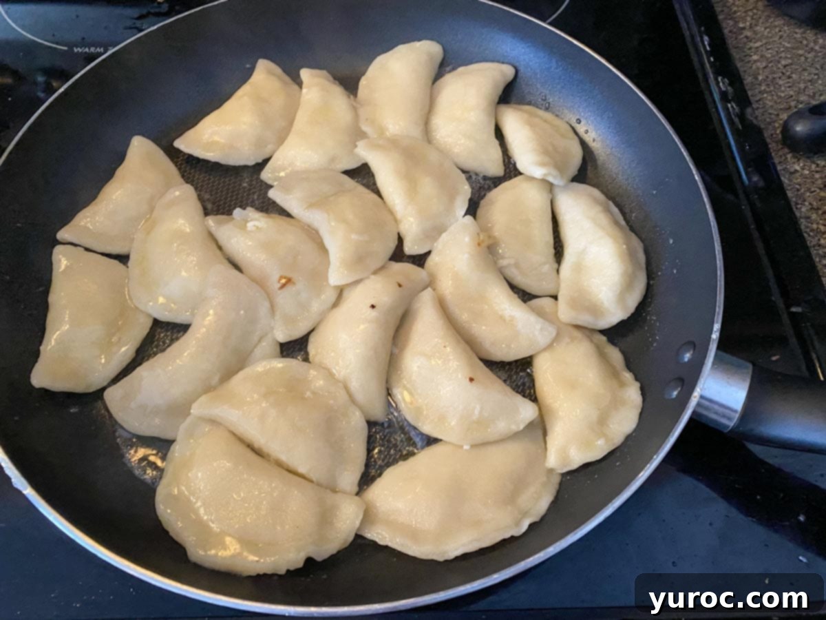 perogies being fried in a large skillet