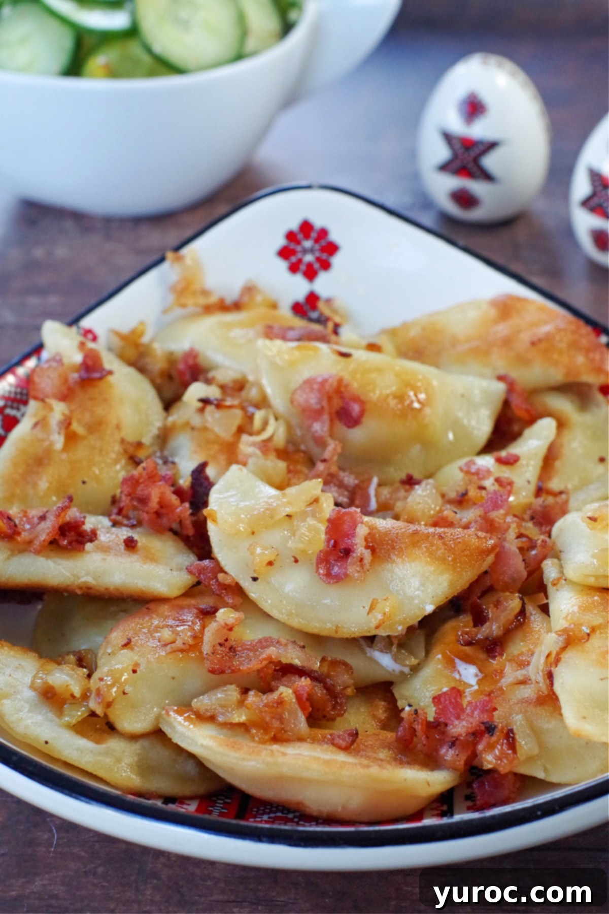 Ukrainian perogies covered in bacon and onion in a ukrainian print dish