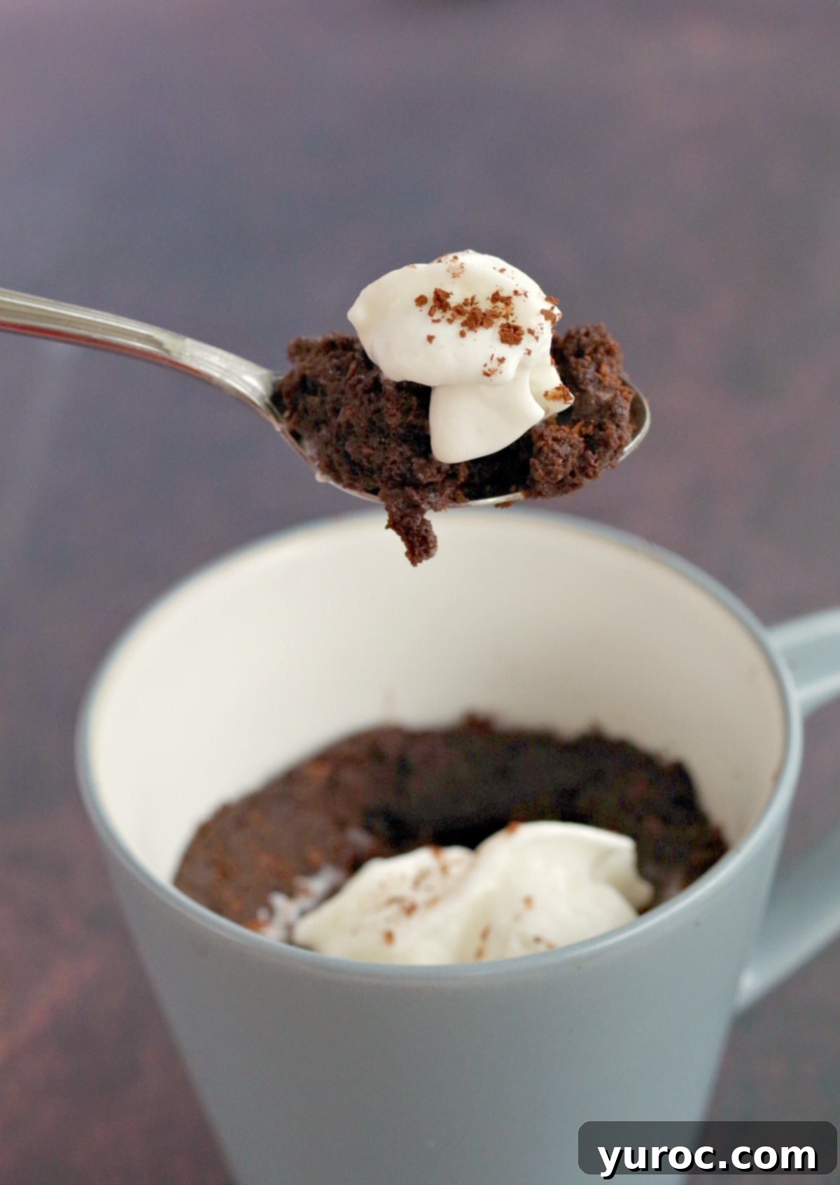 A chocolate mug cake held up on a spoon, showcasing its perfect individual portion size.