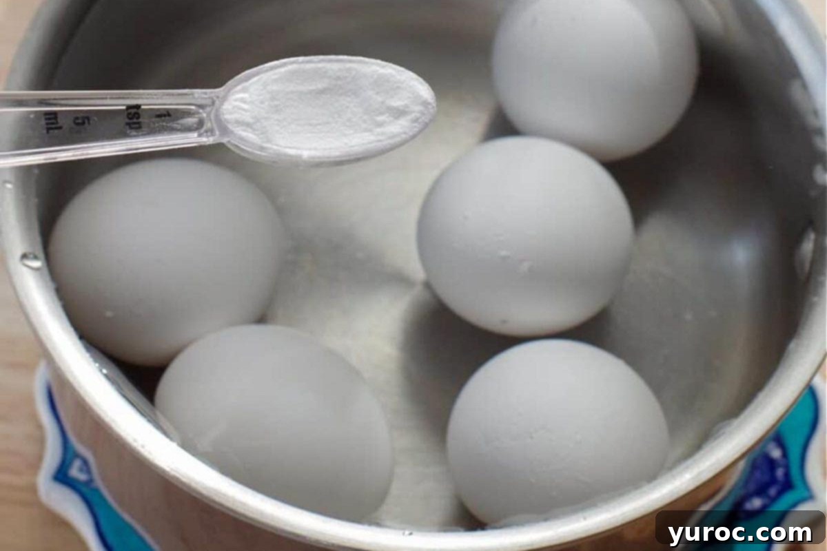 Eggs being boiled in water with a teaspoon of baking soda in a measuring spoon over the pot.