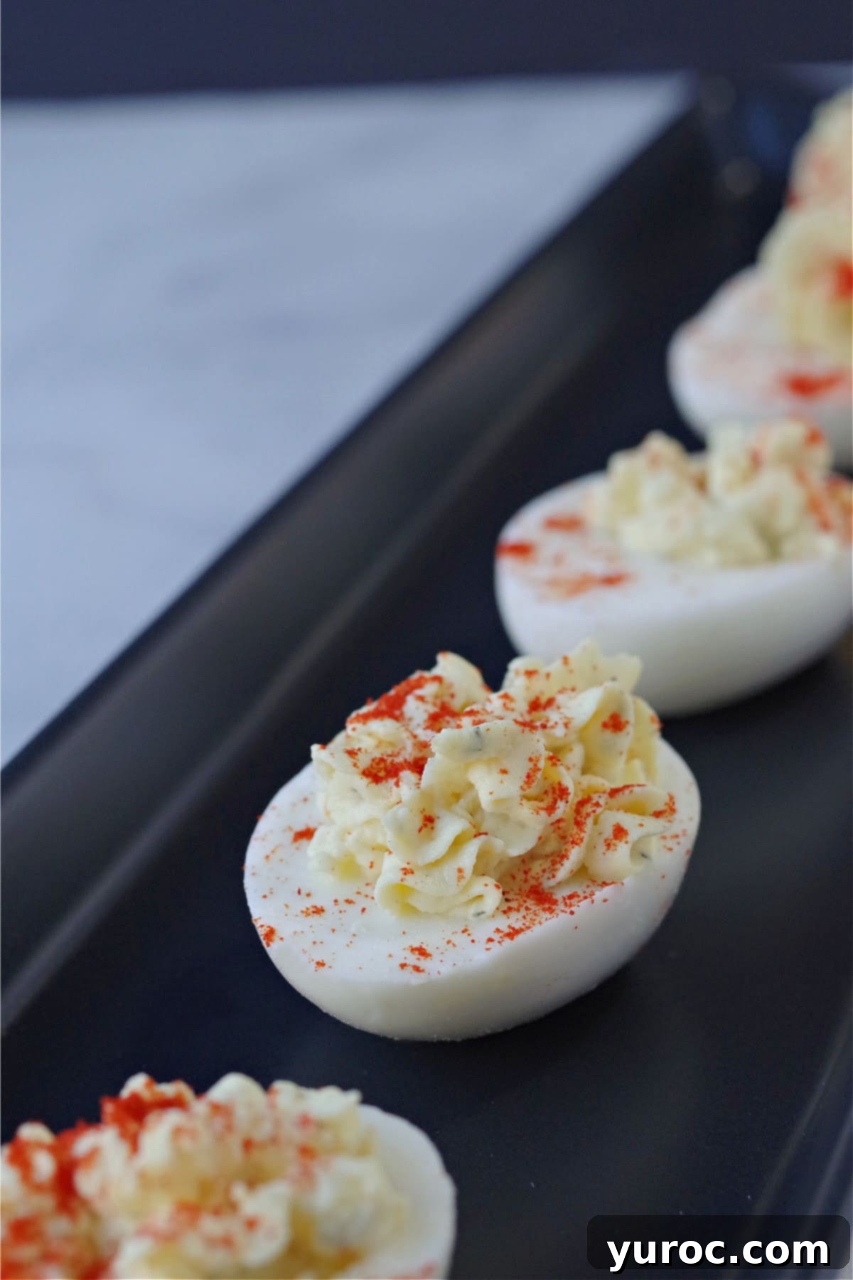 deviled egg with paprika sprinkled on top on black serving tray