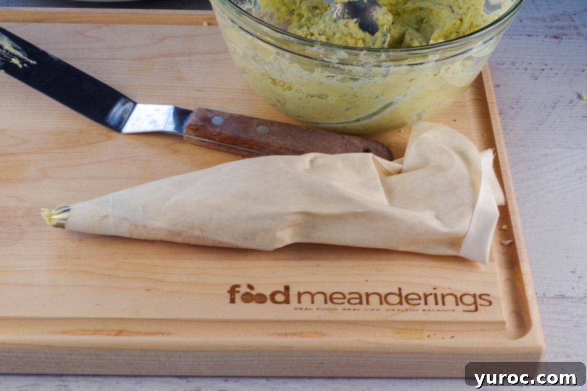 Deviled egg filling in pastry bag with 1M tip on cutting board with off-set spatula