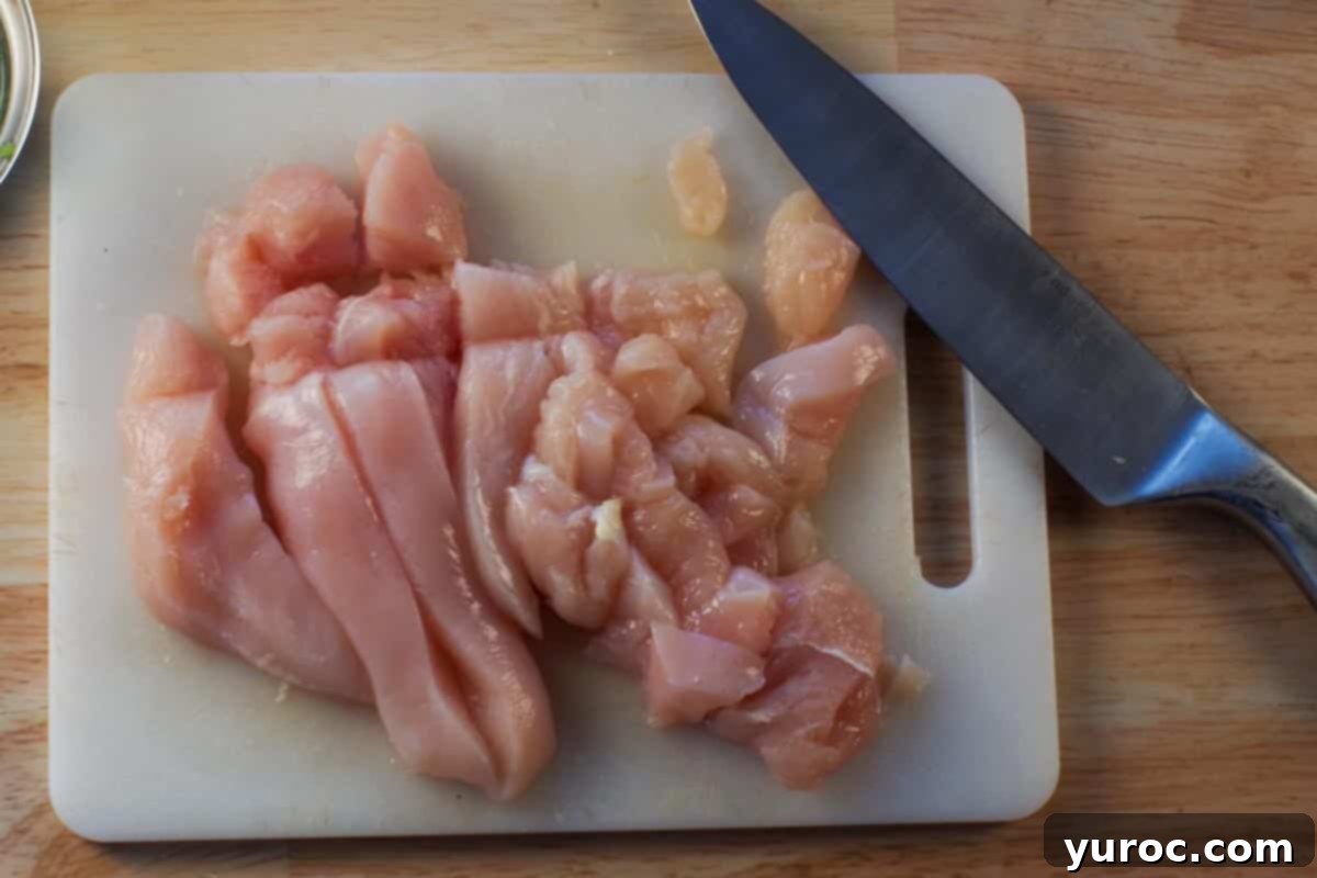 Flavorful and Fit Slow Cooker Mexican Chicken 4 raw chicken breast om white cutting board with sharp knife