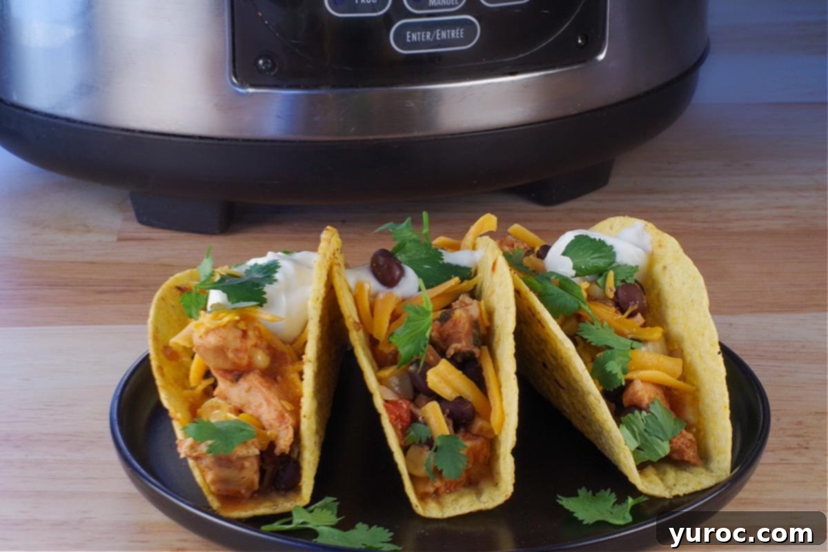 Flavorful and Fit Slow Cooker Mexican Chicken 8 3 Mexican chicken tacos on a black plate with a slow cooker in the background