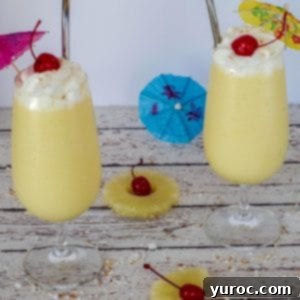 Two healthy Pina Colada drinks on a white faux wood surface with garnishes