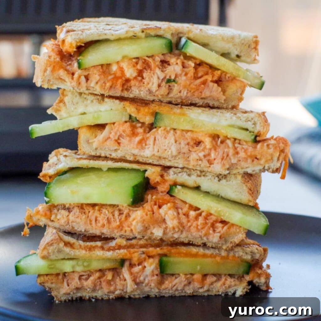 buffalo chicken panini on a black plate with panini press in background