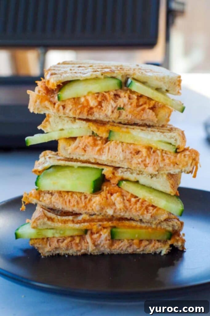 buffalo chicken panini on a black plate with panini press in background