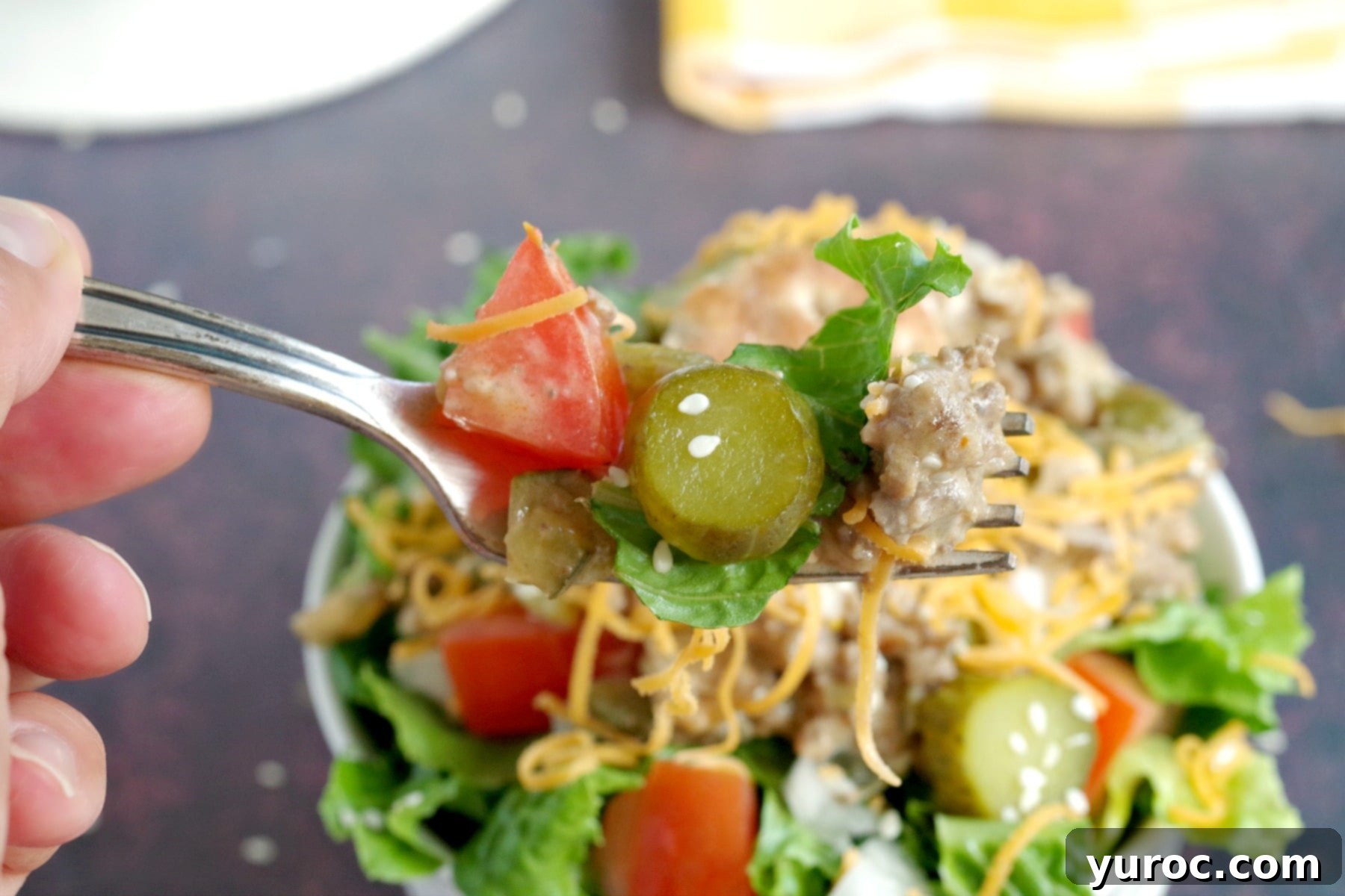 big mac salad being held up on a fork with bowl below