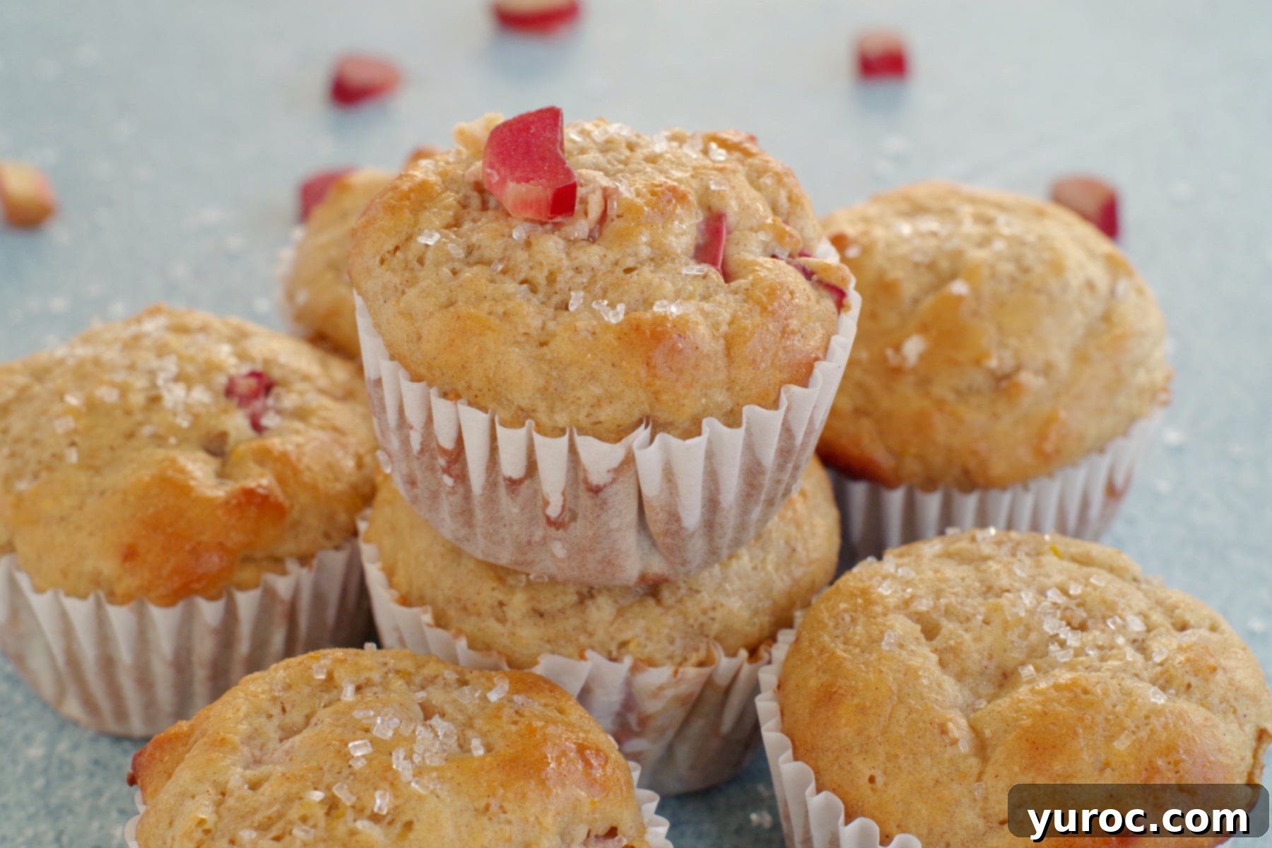 rhubarb muffin stacked on top of other rhubarb muffins with a piece of rhubarb on top