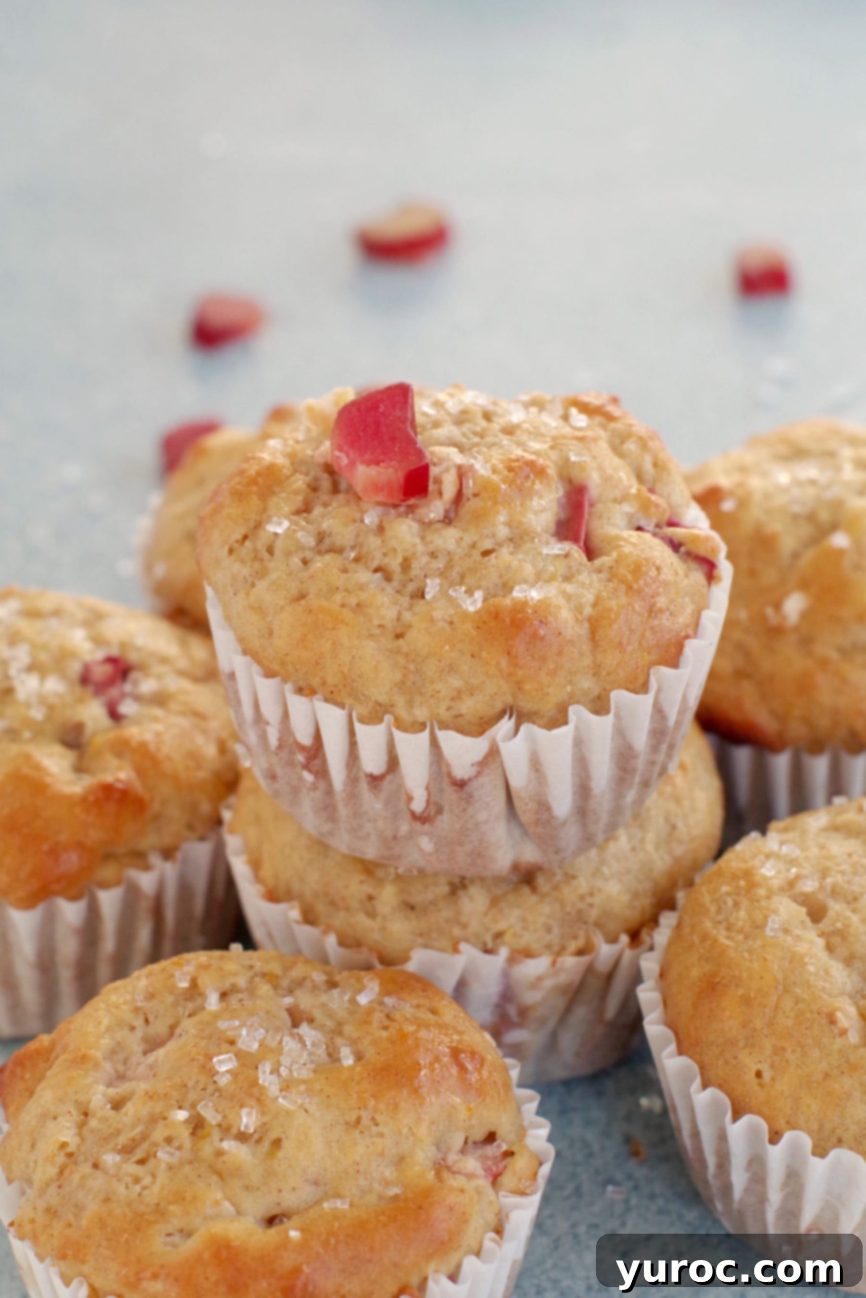 rhubarb muffin stacked on top of other rhubarb muffins with a piece of rhubarb on top