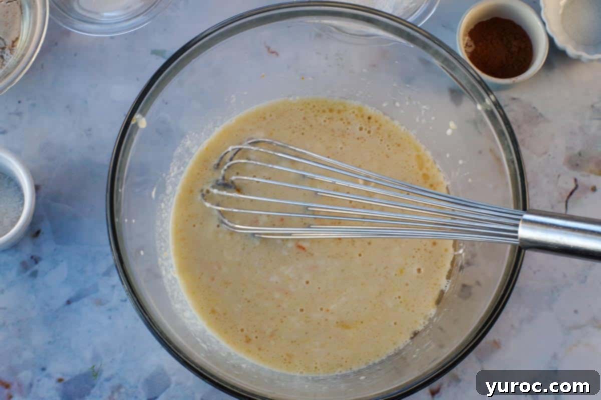 Wet ingredients mixed together in large glass bowl, with whisk.