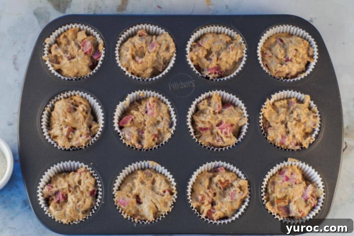 Rhubarb muffin batter spooned into lined muffin tin.