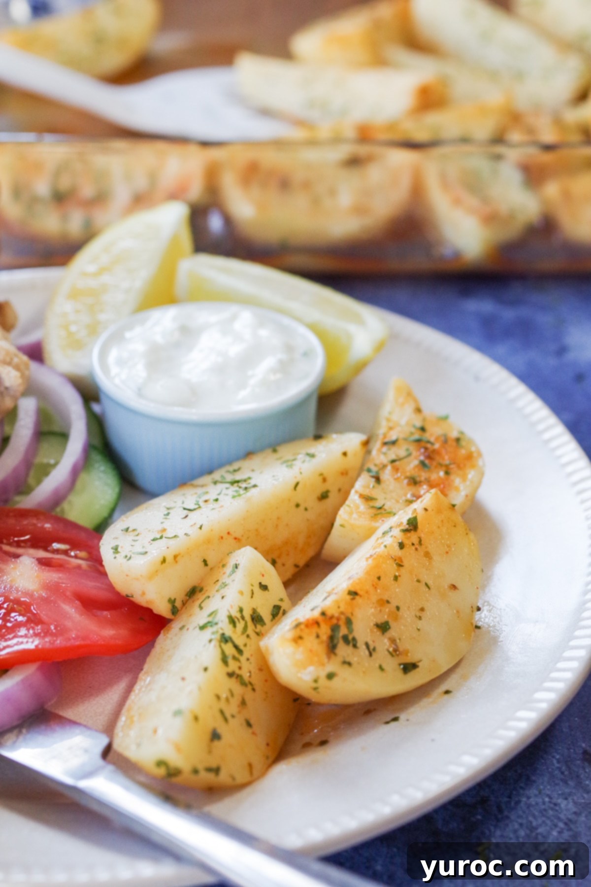 greek style potatoes on a plate with tzatziki and souvlaki