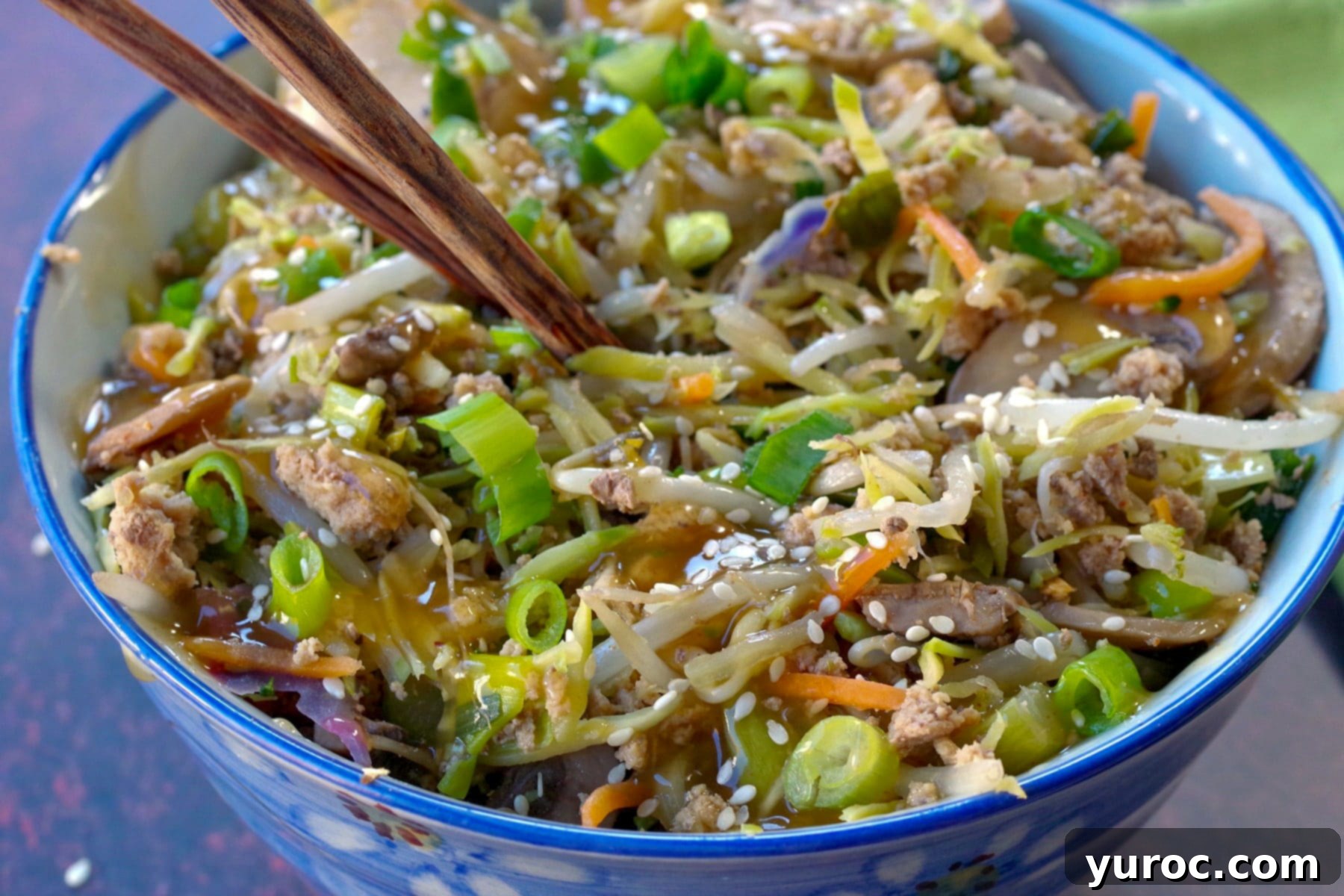 Close up of egg roll in a blue bowl with chopsticks inside