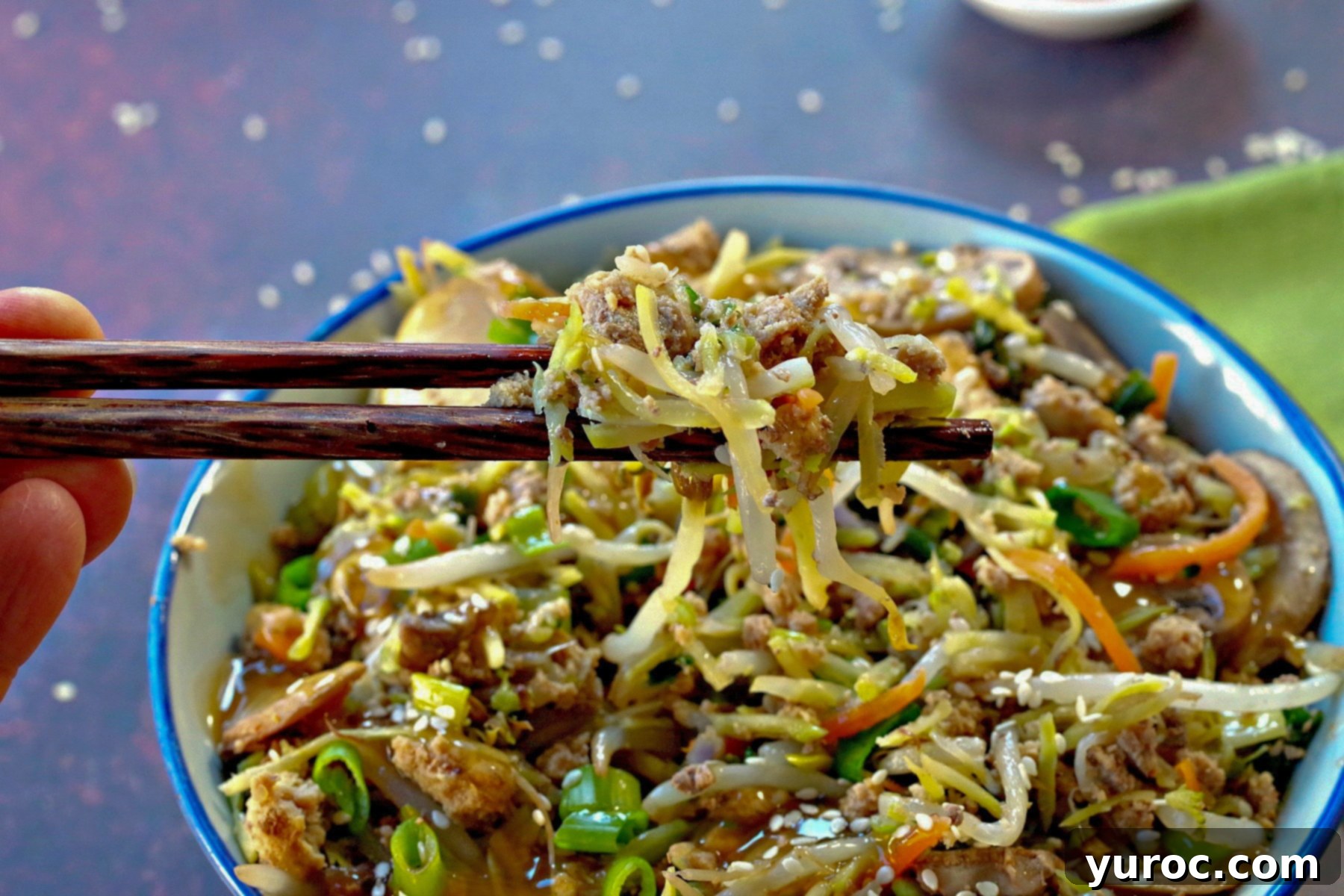 Egg roll in a blue bowl with some being held up with chopsticks