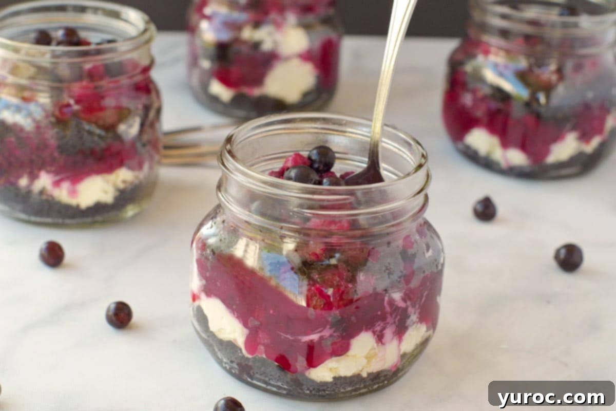 No-Bake Saskatoon Berry Cheesecake Jars 2 no bake saskatoon berry cheesecake in a jar with a spoon and more jars in the background