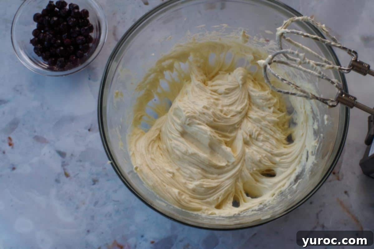 No-Bake Saskatoon Berry Cheesecake Jars 7 Cream cheese, white chocolate and sugar beaten together in glass bowl, with beaters above bowl.