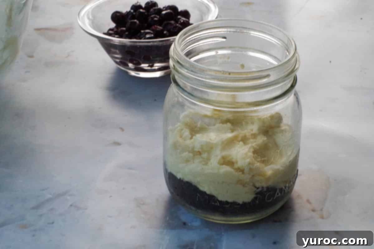 No-Bake Saskatoon Berry Cheesecake Jars 9 Cream cheese added to mason jar on top of chocolate crust.