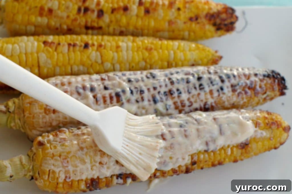 Grilled corn with sauce being spread on it