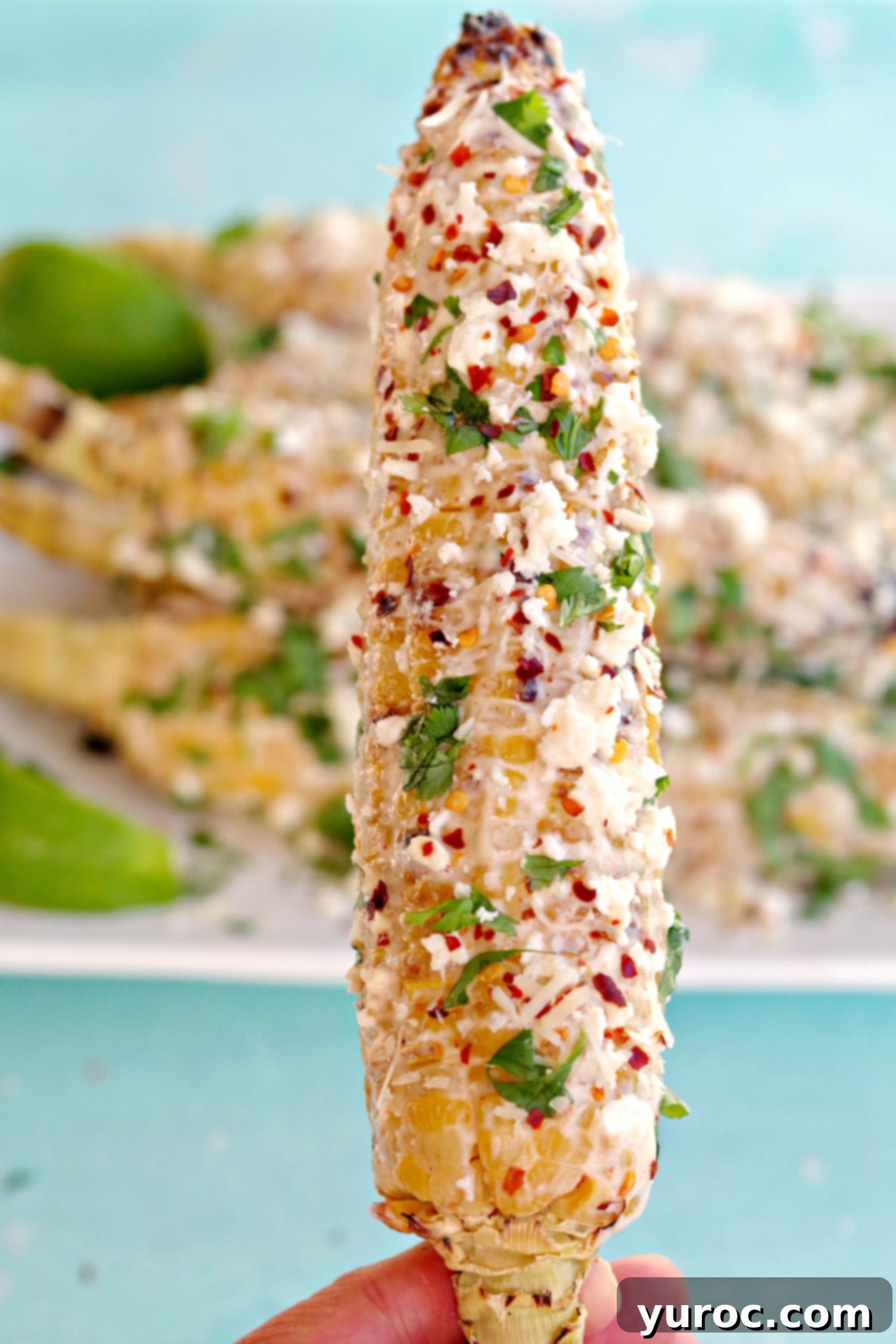 Grilled Mexican Street Corn being held up