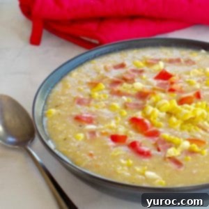 Wholesome Velvety Sweet Corn Chowder 12 Healthy Corn Chowder in a black bowl, with a spoon on the side and red over mitts in background