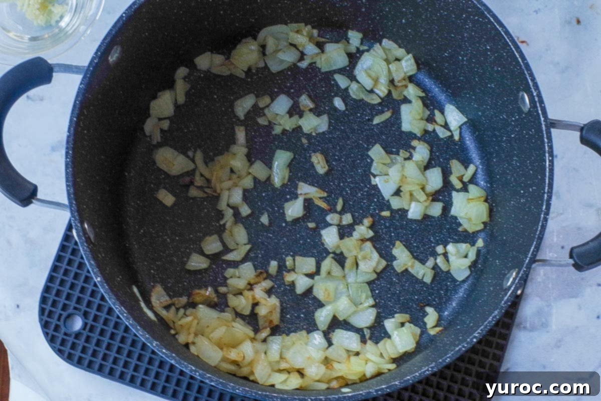 Wholesome Velvety Sweet Corn Chowder 6 Finely chopped onions are shown lightly browned and softened in a large soup pot, indicating the start of the chowder base.