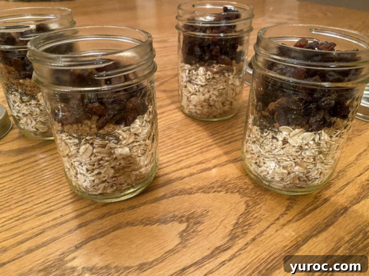 Four small glass jars prepared with individual portions of oats, raisins, brown sugar, and chia seeds on a rustic wooden table.