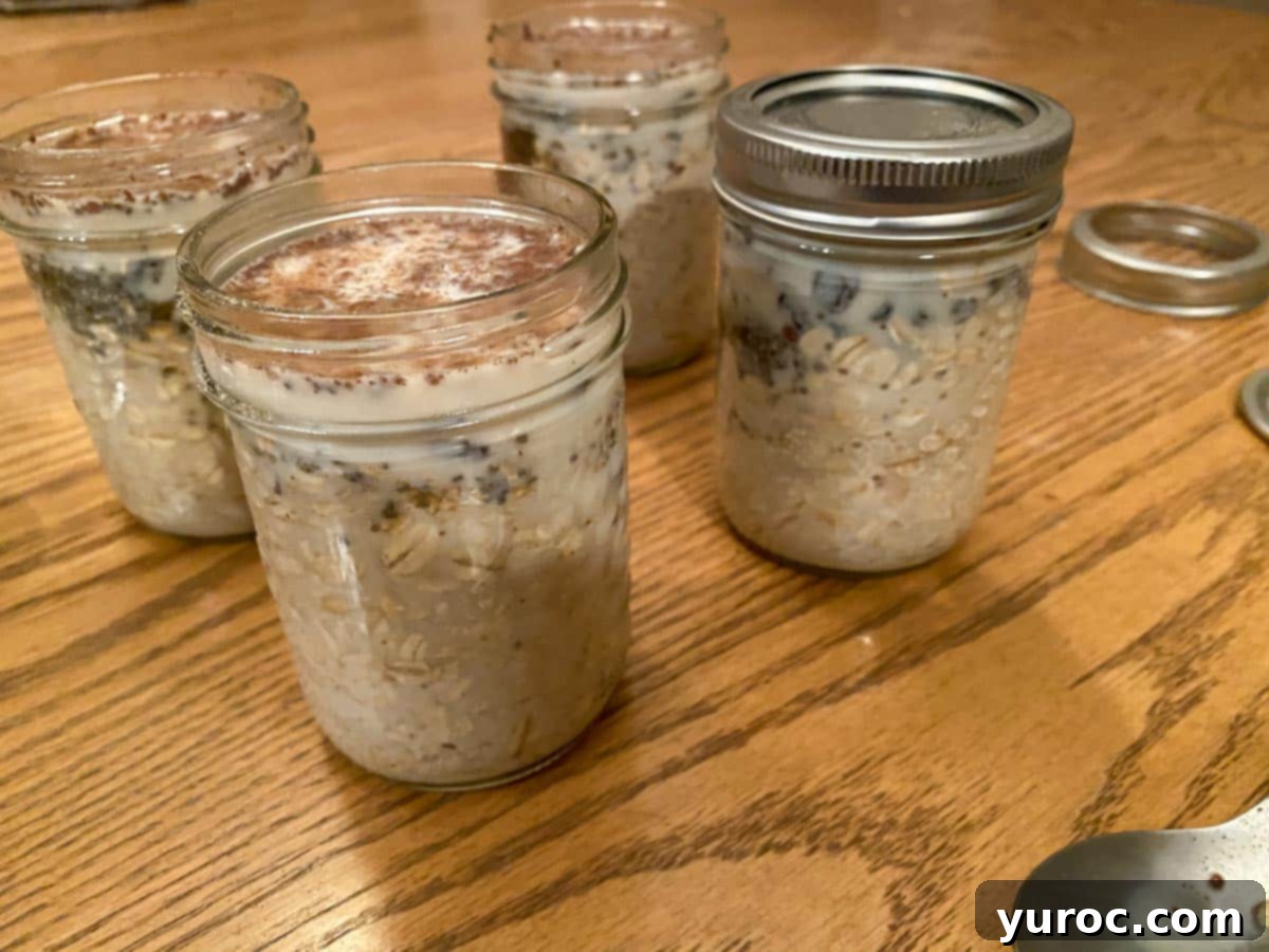 Close-up of glass jars with the oat and raisin mixture gently stirred with milk, ready for refrigeration.