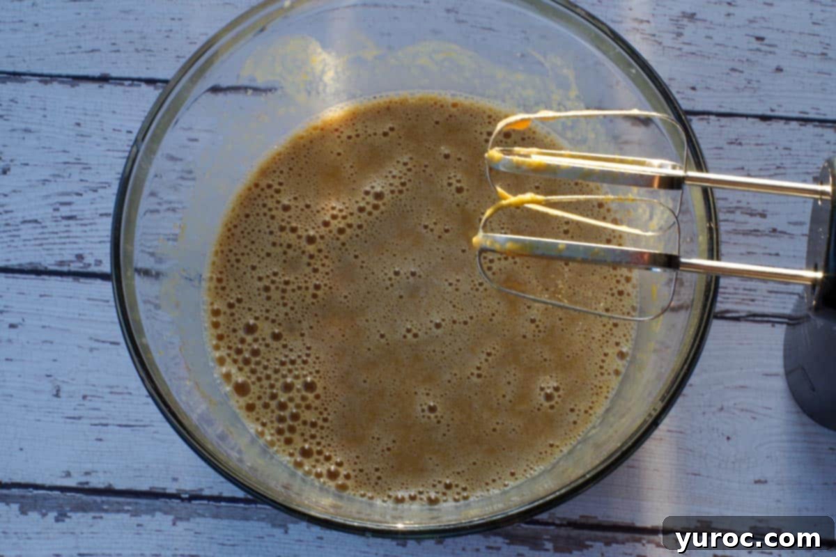 crustless pumpkin pie ingredients blended smoothly together in a glass bowl with electric beaters