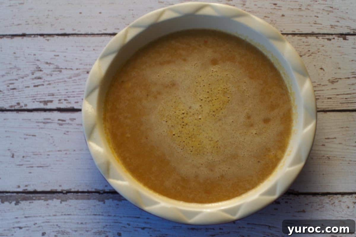 crustless pumpkin pie mixture being poured into a greased pie plate